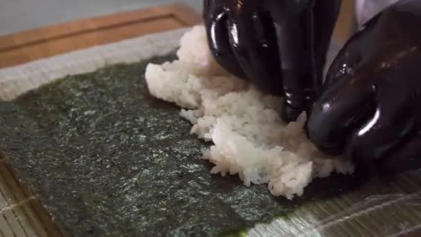 Primo piano delle mani degli chef di sushi, spargendo riso in tutta la zona nori, prima di torcere i rotoli — Video Stock