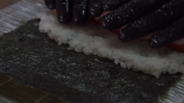 若い寿司職人が米、鮭、海苔を使った日本の寿司ロールを作ります。レストランキッチン、手を閉じる — ストック動画