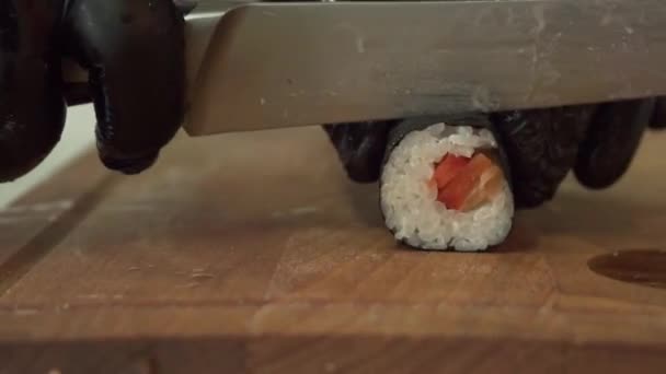 The chef cuts ready-made rolls in the restaurant. Delicious and healthy food. The knife cuts into parts of the land. Sushi with salmon — Stock Video