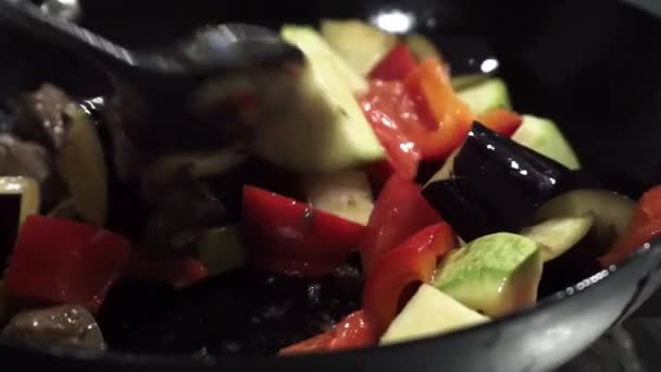 蔬菜在烹调过程中与汤匙混合.锅里有蔬菜的油炸肉 — 图库视频影像