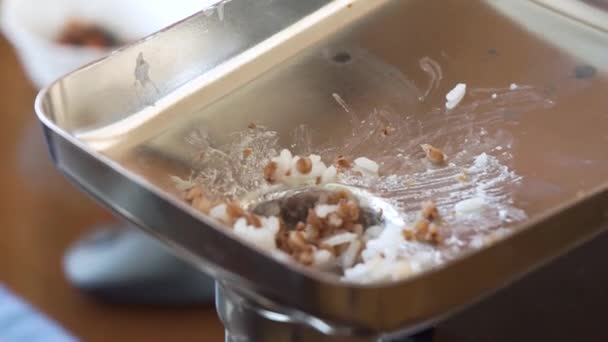 Seorang wanita menambahkan tablespoon beras cincang dan buckwheat groats ke grinder.The pendorong dari penggiling daging mendorong isi — Stok Video