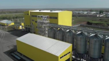 Tanklarda depolamak için tarım ambarı. Fabrikadaki üretim tesisleri. Sarı binalar ve tahıl asansörleri