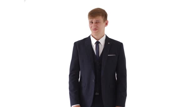 Puzzled young man 20 years old in a white dress shirt and classic, isolated on a white studio background, portrait. Lifestyle concept, people emotions. Shows discontent.4k — Stock Video