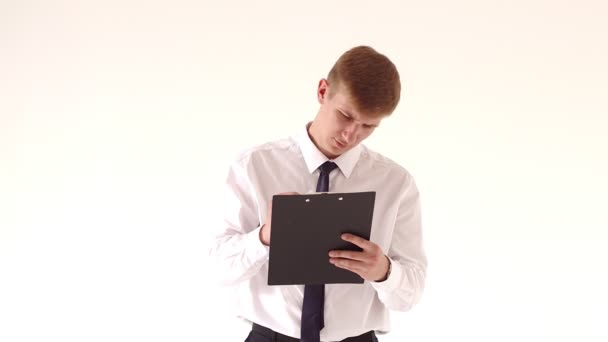 Zakenman schrijft in documentatie geïsoleerd op witte achtergrond. Blanke zakenman in een shirt en stropdas op zoek naar documenten in zijn handen op een witte scherm achtergrond — Stockvideo