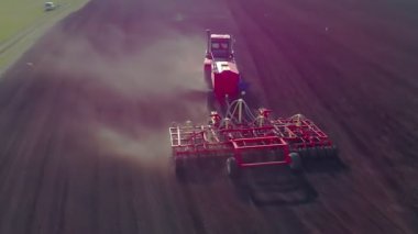 Gün batımında, gün doğumunda tarlayı süren büyük, modern ve güçlü bir sabanın havadan görünüşü. Tarım, arazi ekimi. Gıda endüstrisi kavramı