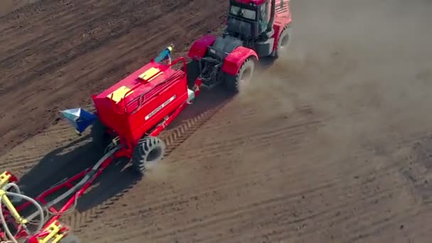 En traktor som använder jordbruksmaskiner sår ett fält. Automatisering av produktionen, arbete på fältet. Fågelöga. En traktor med en harv gård i fält — Stockvideo