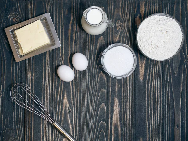 Un, yumurta, süt ve şekerin üst görüntüsü mutfaktaki masada.