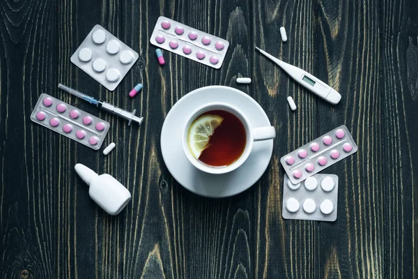 Vista superior da xícara de chá, pílulas e termômetro em fundo de madeira. — Fotografia de Stock