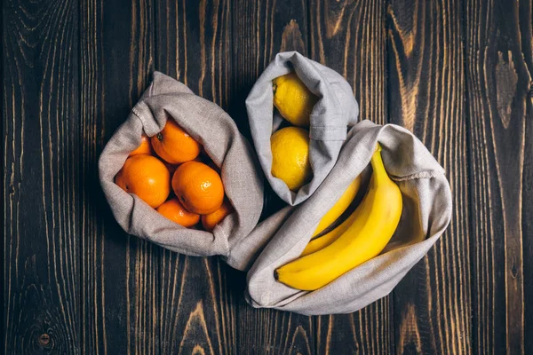 Tahta masada, geri dönüşümlü eko poşetlerde taze meyveler.