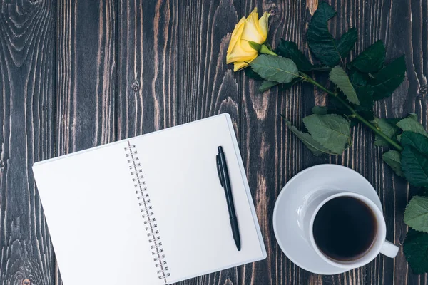 Not defteri, bir fincan kahve ve ahşap arka planda sarı gül. maket yap