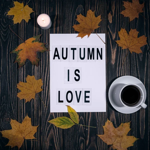 Blick von oben auf Herbstblätter, Kaffeetasse und Herbstschrift auf Holzgrund — Stockfoto