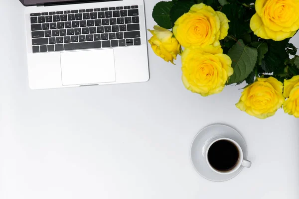 Kadın işyeri, sarı güller, dizüstü bilgisayar ve kupa beyaz arka planda