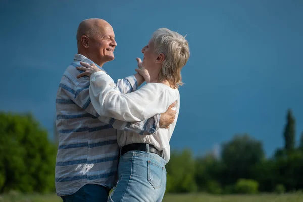 Счастливая старшая пара имеют романтические свидания и танцы в солнечный день на открытом воздухе — стоковое фото