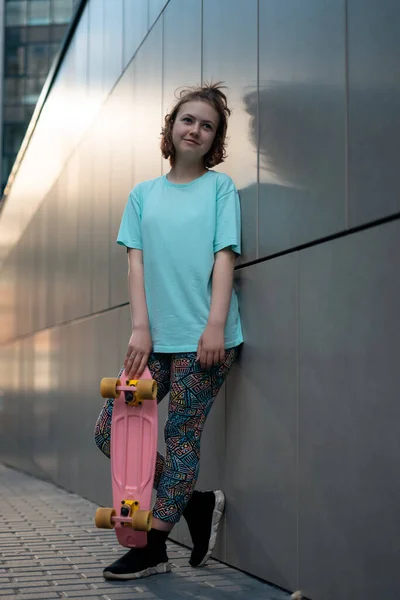 Güzel genç kız güneşli bir günde sokakta elinde bozuk para tahtasıyla dikiliyor.