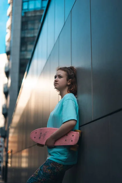 Güzel genç kız güneşli bir günde sokakta elinde bozuk para tahtasıyla dikiliyor.