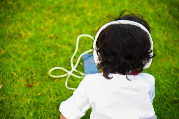 Çocuk büyük beyaz kulaklıkla müzik dinliyor. Metin için boşluk .