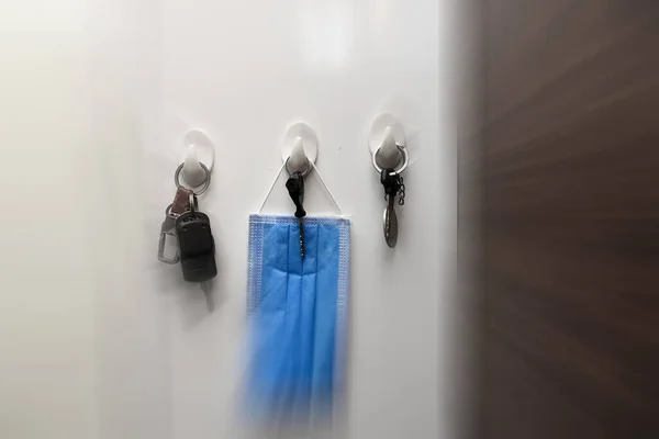 Anahtarlar ve tıbbi yüz maskesi hareket bulanıklığı olan bir askıda asılı. Yeni yaşam tarzı kavramı .
