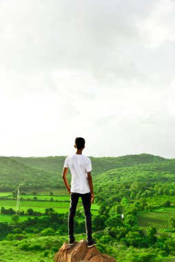 Adam dağın tepesinde duruyor ve doğanın yeşilliğini seyrediyor. Doğanın mucizesi harika bir an..