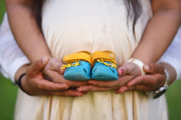 Yeni doğmuş bebek popoları ebeveynlerin elinde, hamile kadın göbeği. Annelik kavramı .