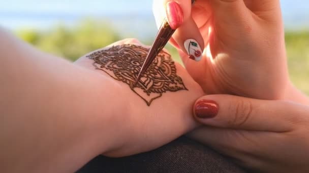 Woman draws henna on her hand outdoors — Stock Video