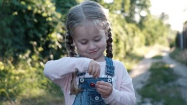 Küçük kız yaz parkta kiraz yiyor.