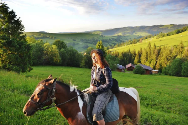 A woman is sitting on a horse in the mountains