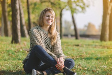 sarışın parkta yeşil çimenlerin üzerinde oturuyor