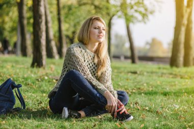 sarışın parkta yeşil çimenlerin üzerinde oturuyor