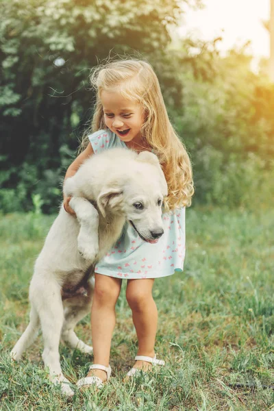 Kis aranyos szőke lány játszik vele kiskutya golden retriever. — Stock Fotó
