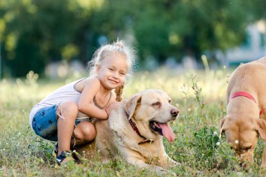 Küçük kız yaz parkında Labrador 'la oynuyor..