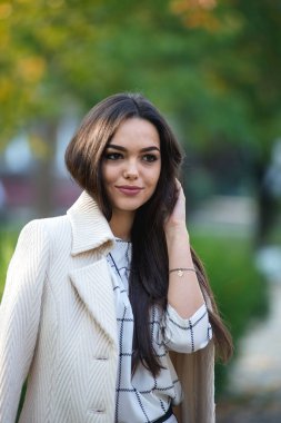 Genç güzel iş kadını sonbaharda parkta duruyor.