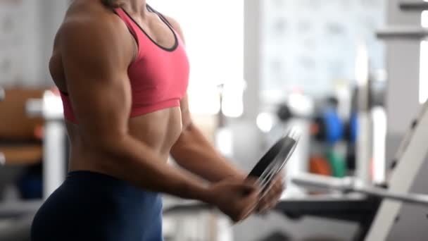 Athlète femme entraîne les muscles avec des poids dans la salle de gym . — Video