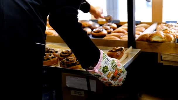 Der Konditor legt in der Bäckerei frisches Gebäck auf dem Schaufenster aus. — Stockvideo