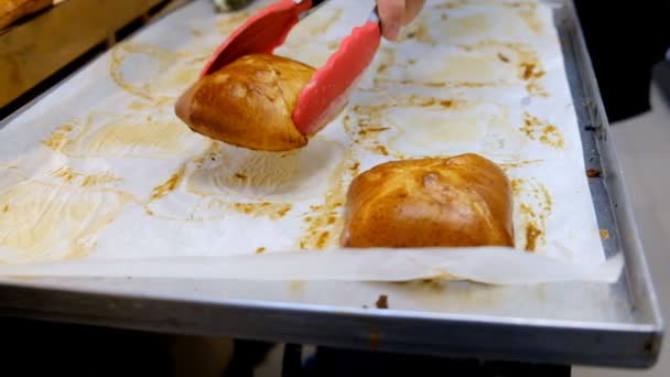 Cukrář vyloží čerstvým pečivem na průčelí v pekárně. — Stock video