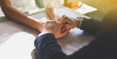 Bir çift bir kafede masada oturuyor. Bir adam bir kızın elini tutar.