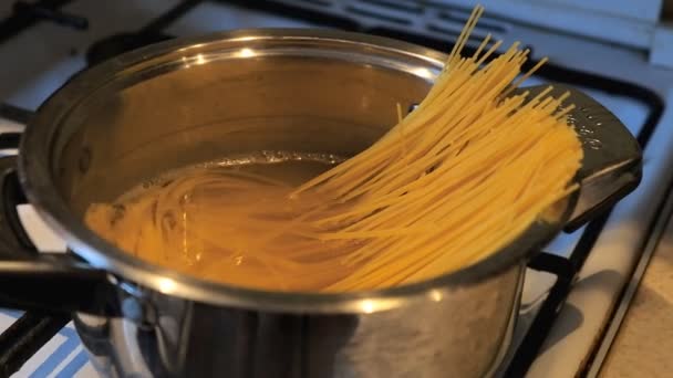 Gli spaghetti vengono cotti in padella. Un cucchiaio donna impedisce gli spaghetti nella padella . — Video Stock