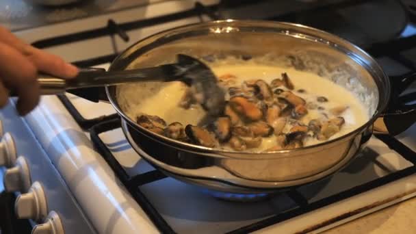 Femme cuisine des moules dans une sauce à la crème dans une poêle . — Video