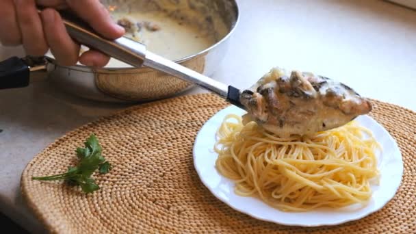 Vrouw zet mosselen in een romige saus in een bord met pasta. — Stockvideo