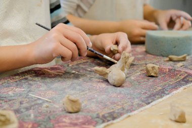 Bir çocuk modellik dersinde bir ürünü kilden şekillendirir..