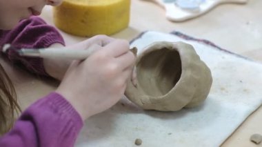 Çocuk seramik atölyede farklı türde kil ürünleri şekillendirmeyi öğreniyor. Çocuk, yaratıcı bir derste kilden bağımsız olarak çalışır..