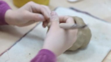 Çocuk seramik atölyede farklı türde kil ürünleri şekillendirmeyi öğreniyor. Çocuk, yaratıcı bir derste kilden bağımsız olarak çalışır..