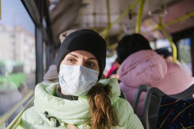 genç bir kadın koruyucu tıbbi maskeli bir otobüs rides. Bir kadın toplu taşıma virüslerden koruma.