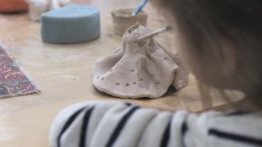 Çocuk seramik atölyede farklı türde kil ürünleri şekillendirmeyi öğreniyor..