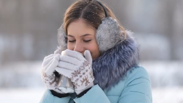 Young beautiful woman drinks hot tea in winter in the park — Stock Video