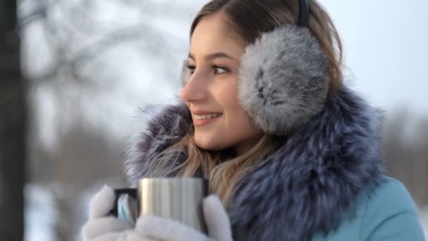 Jovem bela mulher bebe chá quente no inverno no parque — Vídeo de Stock