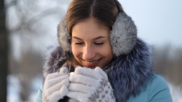 Jonge mooie vrouw drinkt warme thee in de winter in het park — Stockvideo