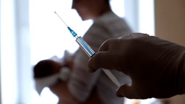 医者は赤ん坊に注射するためにワクチンで注射器を準備する. — ストック動画