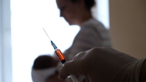 De arts bereidt een spuit met een vaccin voor om de baby een injectie te geven.. — Stockvideo