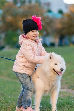 küçük kız köpeğini Samoyed Park ile yürüyor