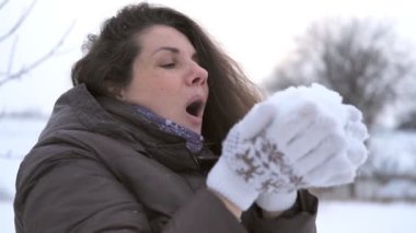 Kadın kışın avuçlarından kar üflüyor..